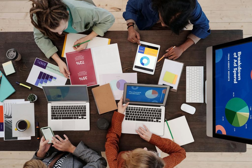 A diverse team collaborating on digital marketing strategies at a desk, using laptops and tablets.