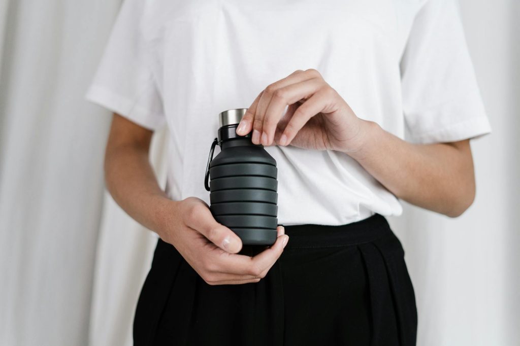 A person holding a collapsible black water bottle, promoting zero waste lifestyle.