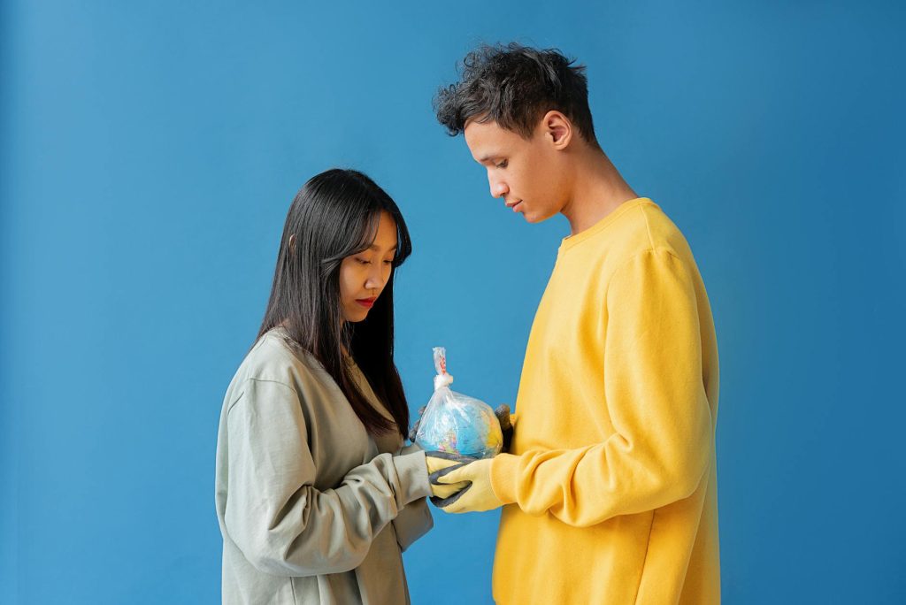 A couple holding a globe wrapped in plastic highlighting ecological responsibility and environmental protection.