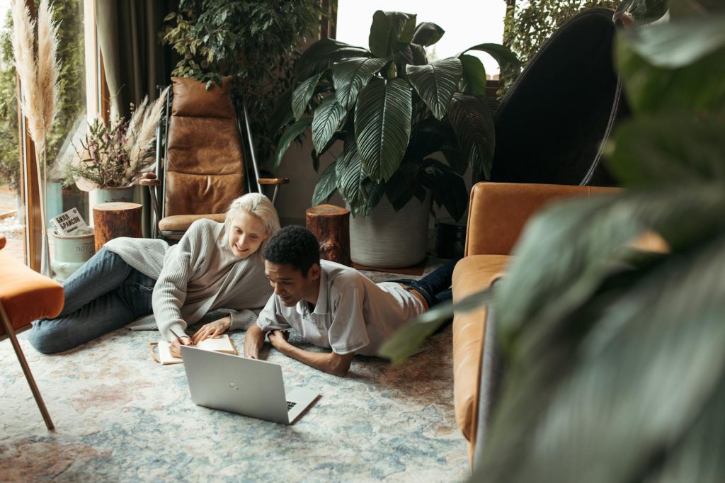 Two adults collaborating in a modern, indoor creative workspace with a laptop.