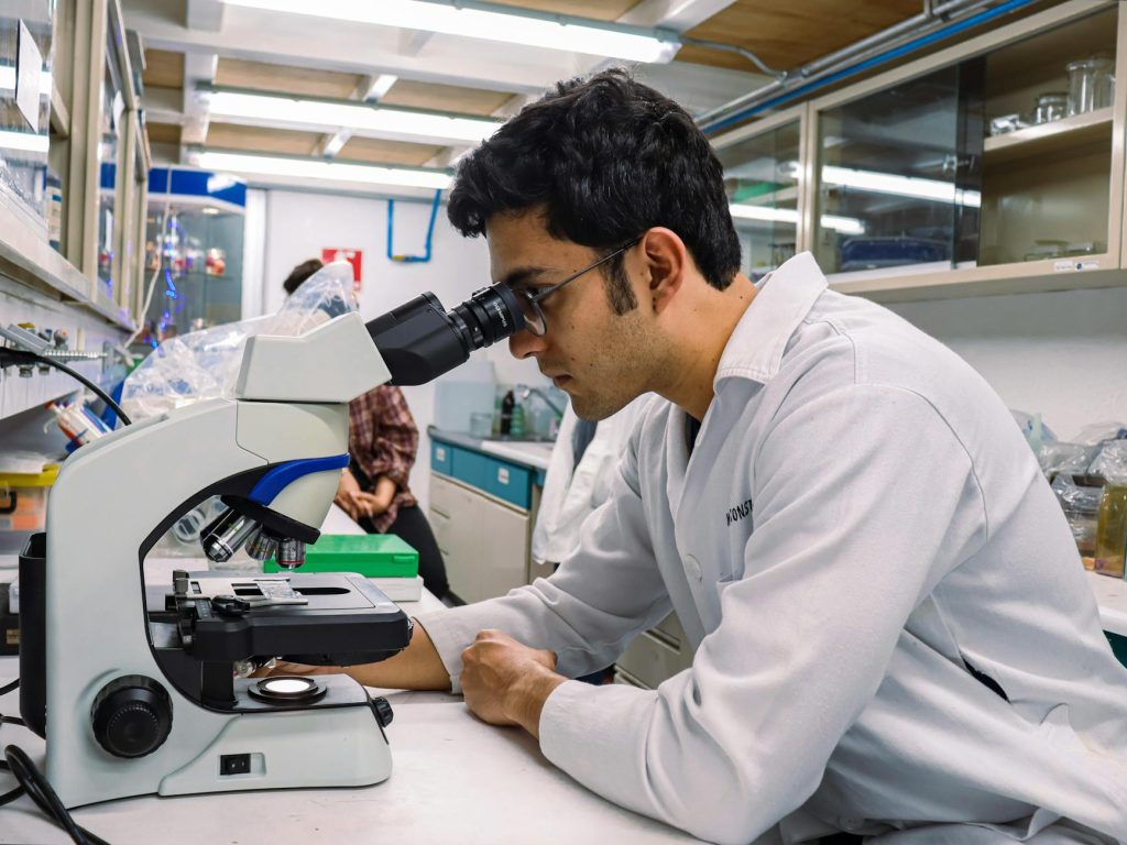 A scientist focused on examining a sample with a microscope in a laboratory setting.