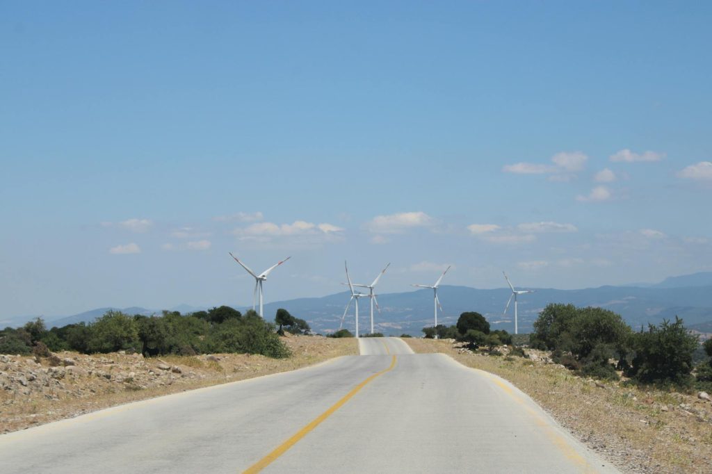 Scenic road in Behram, Türkiye with distant wind turbines and clear blue sky