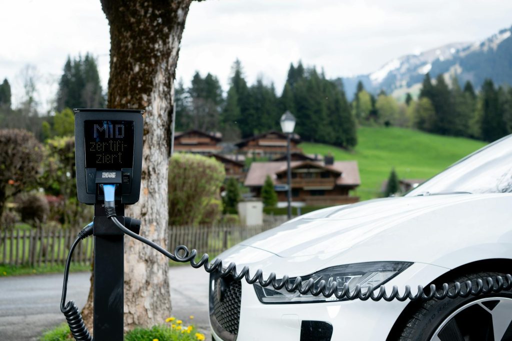 Electric car charging at a station in a picturesque mountain village, promoting sustainable transportation.