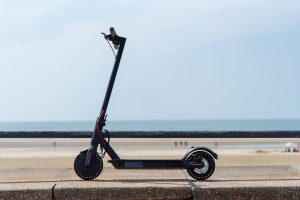 Sleek electric scooter parked by a scenic beachside on a clear day.