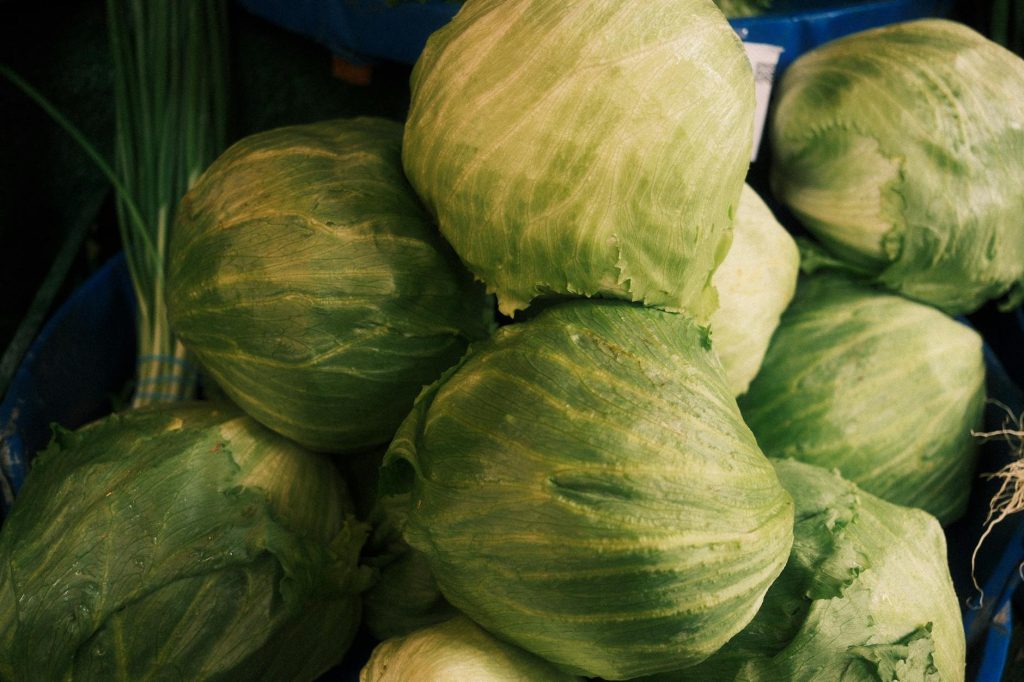 A stack of fresh green cabbages displayed at an outdoor market