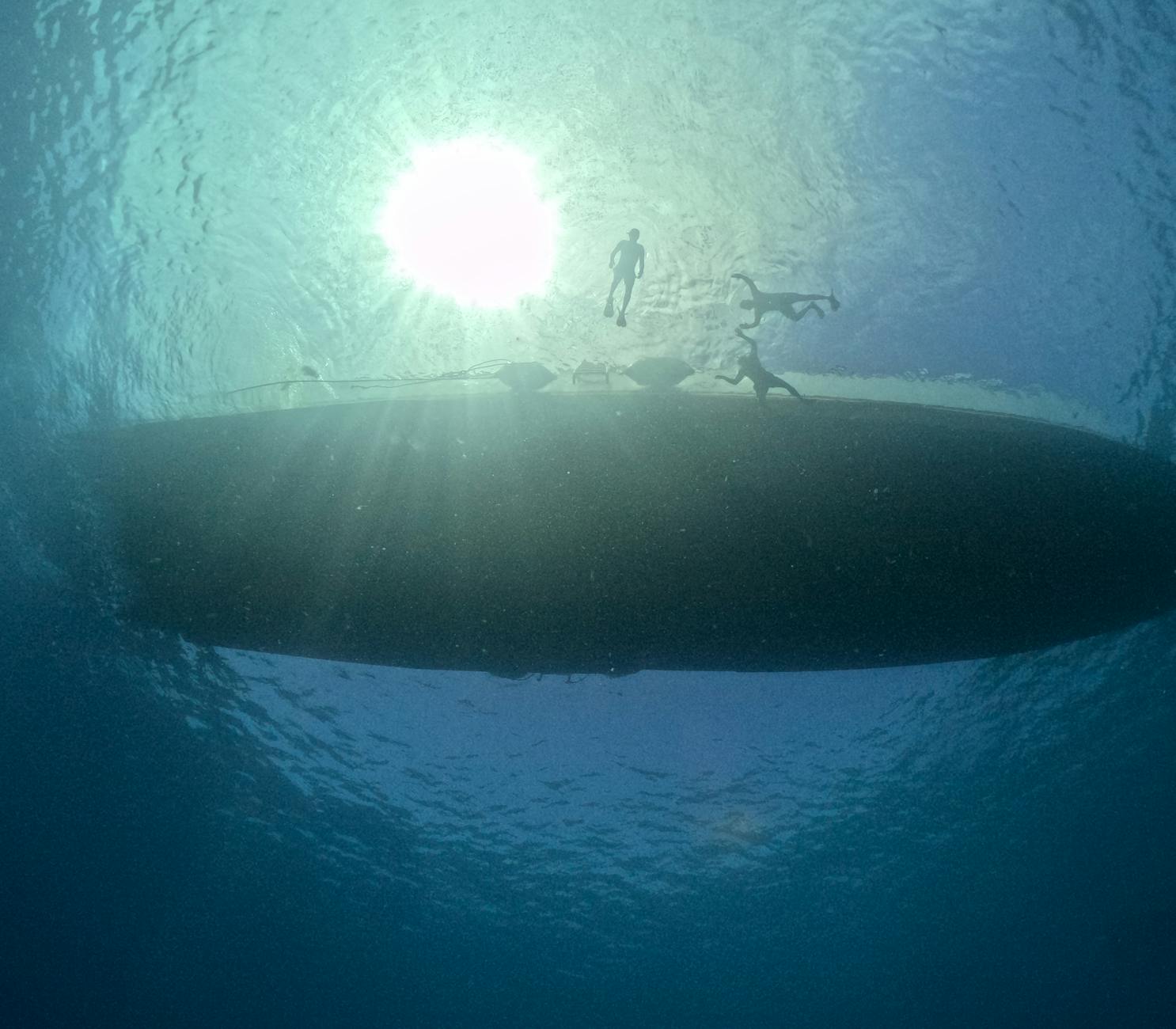 underwater view of people swimming near boat